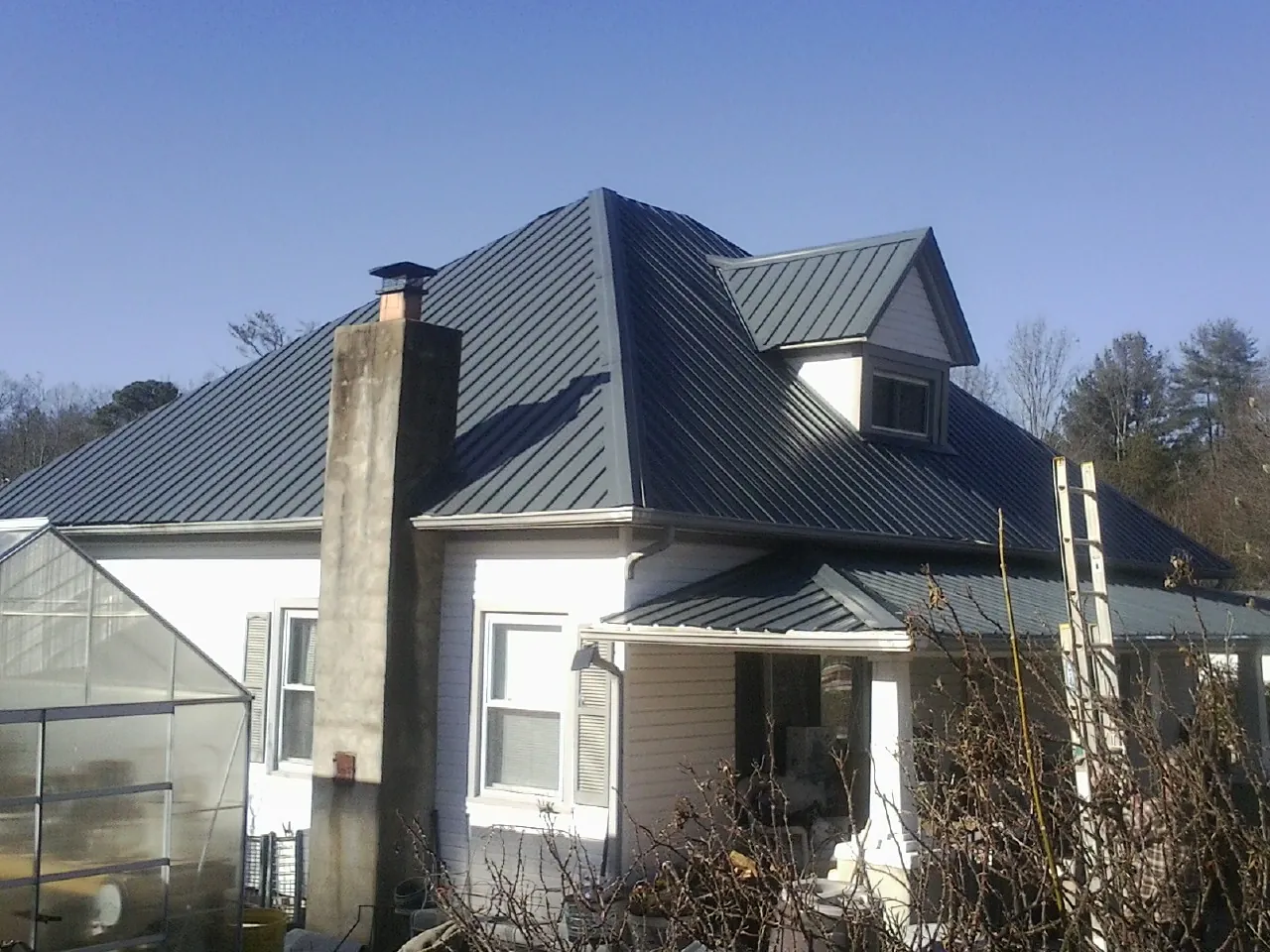 Dark blue standing seam metal roof on a white farmhouse with dormer — Slate & Tile Roof Repair by Roofing Brothers in Soldier
