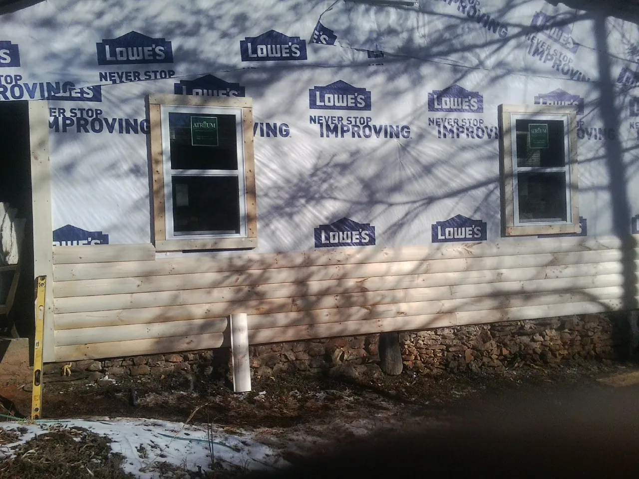 House wrap and new log siding going up on an exterior wall in Soldier