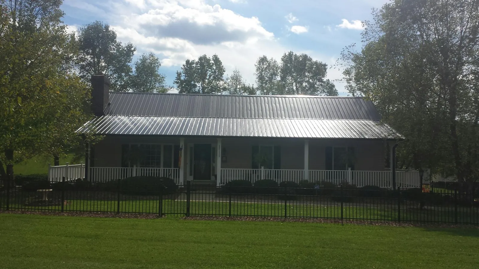 Gray metal roof on a brick ranch with a full width front porch — Gutter Guard Installation work by our crew in Soldier